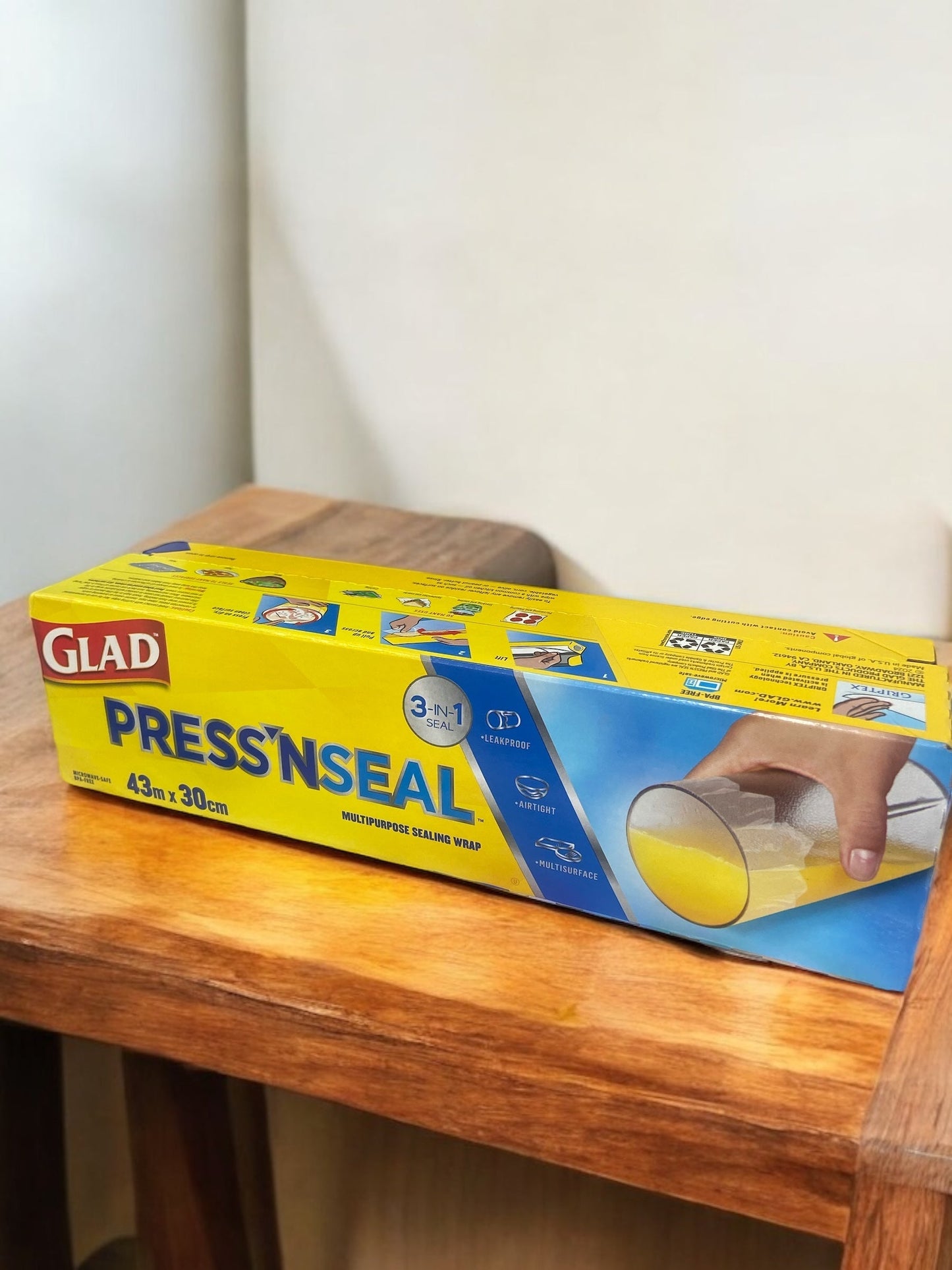 GLAD Press'n Seal storage wrap on a wooden table, showcasing vacuum sealing and griptex technology for fresh food storage.