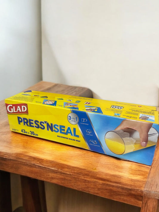 GLAD Press'n Seal storage wrap on a wooden table, showcasing vacuum sealing and griptex technology for fresh food storage.