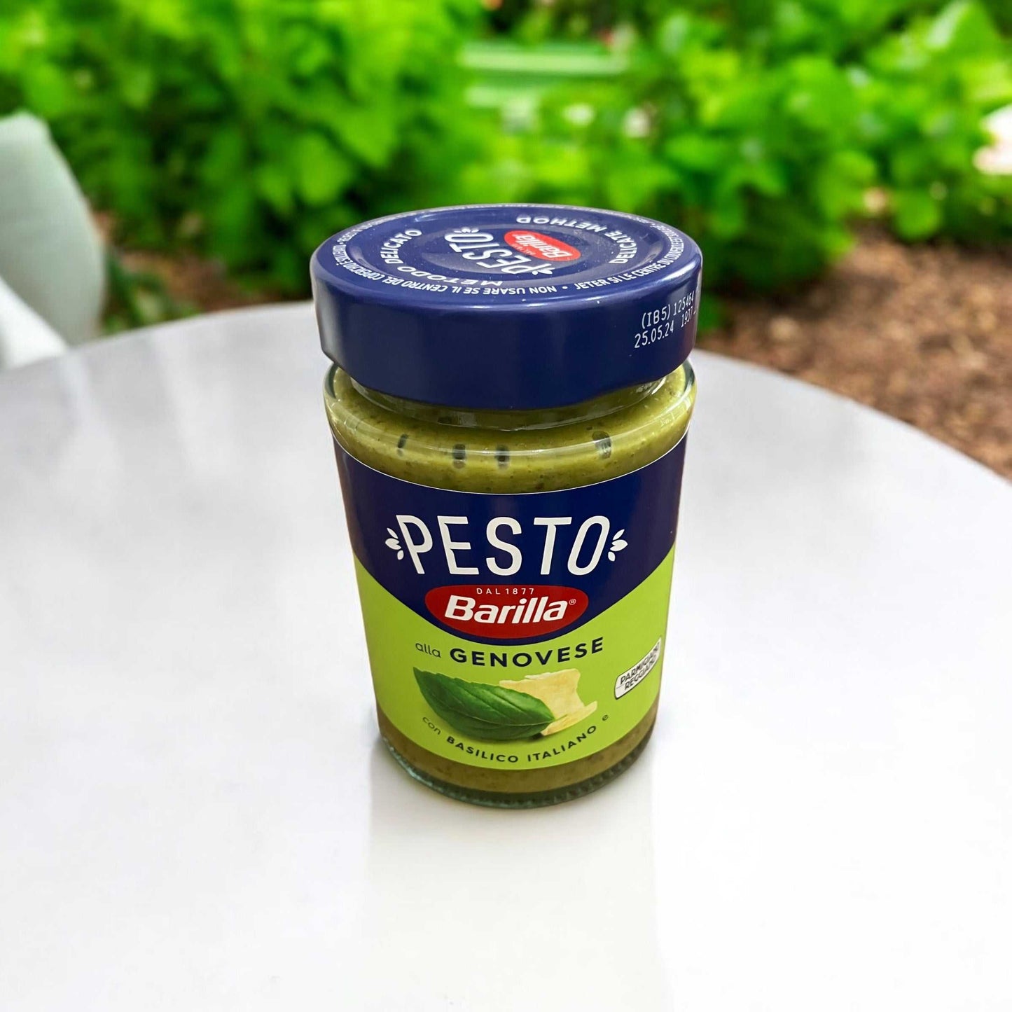 バリラ ジェノベーゼソース パスタソース 190g jar on a table, featuring Italian basil and Parmigiano Reggiano.