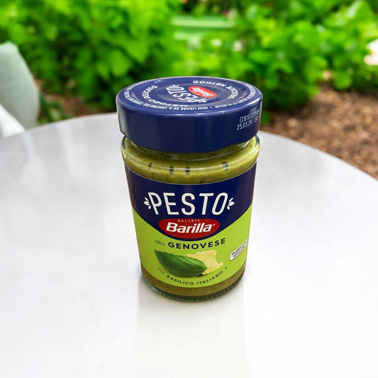 バリラ ジェノベーゼソース パスタソース 190g jar on a table, featuring Italian basil and Parmigiano Reggiano.