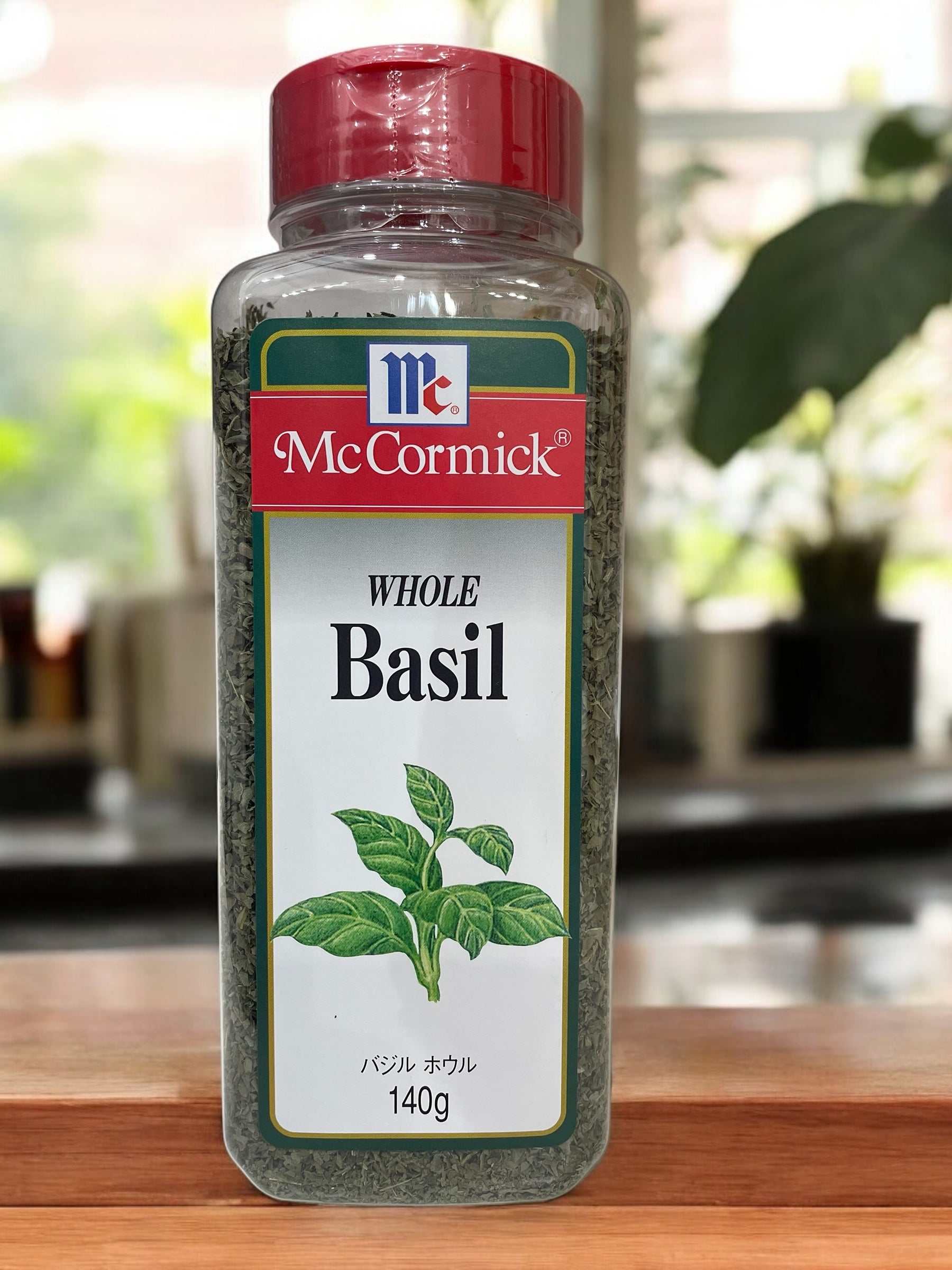 McCormick Whole Basil 140g with red cap in kitchen setting.