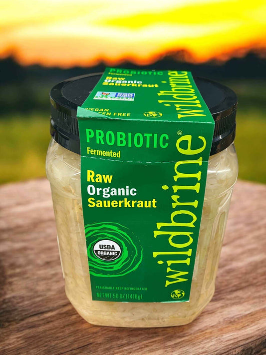 Jar of Wildbrine raw organic sauerkraut with USDA organic label against a sunset background