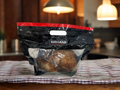 Rotisserie chicken in Kirkland packaging on a kitchen table.